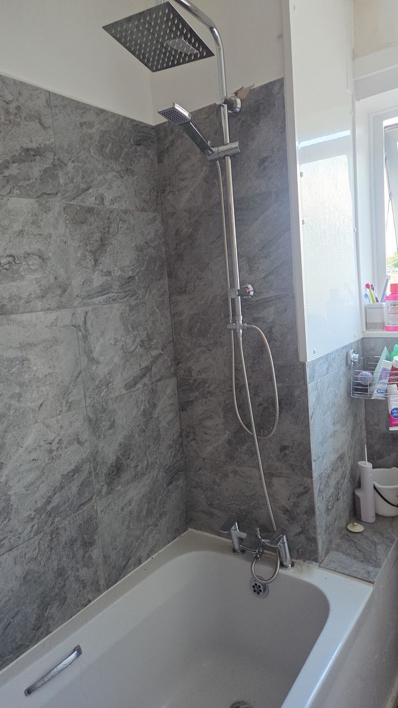 Finished bathroom with grey marble-effect tiling and a chrome shower set
