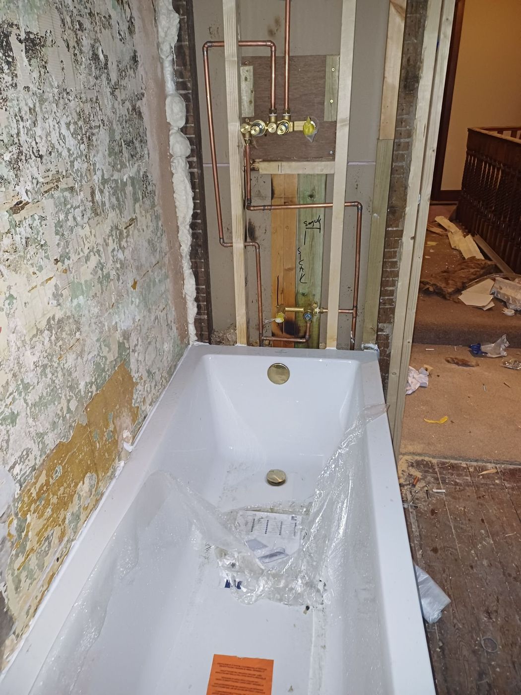 Bathroom mid-refit with walls stripped back and the bath set in place