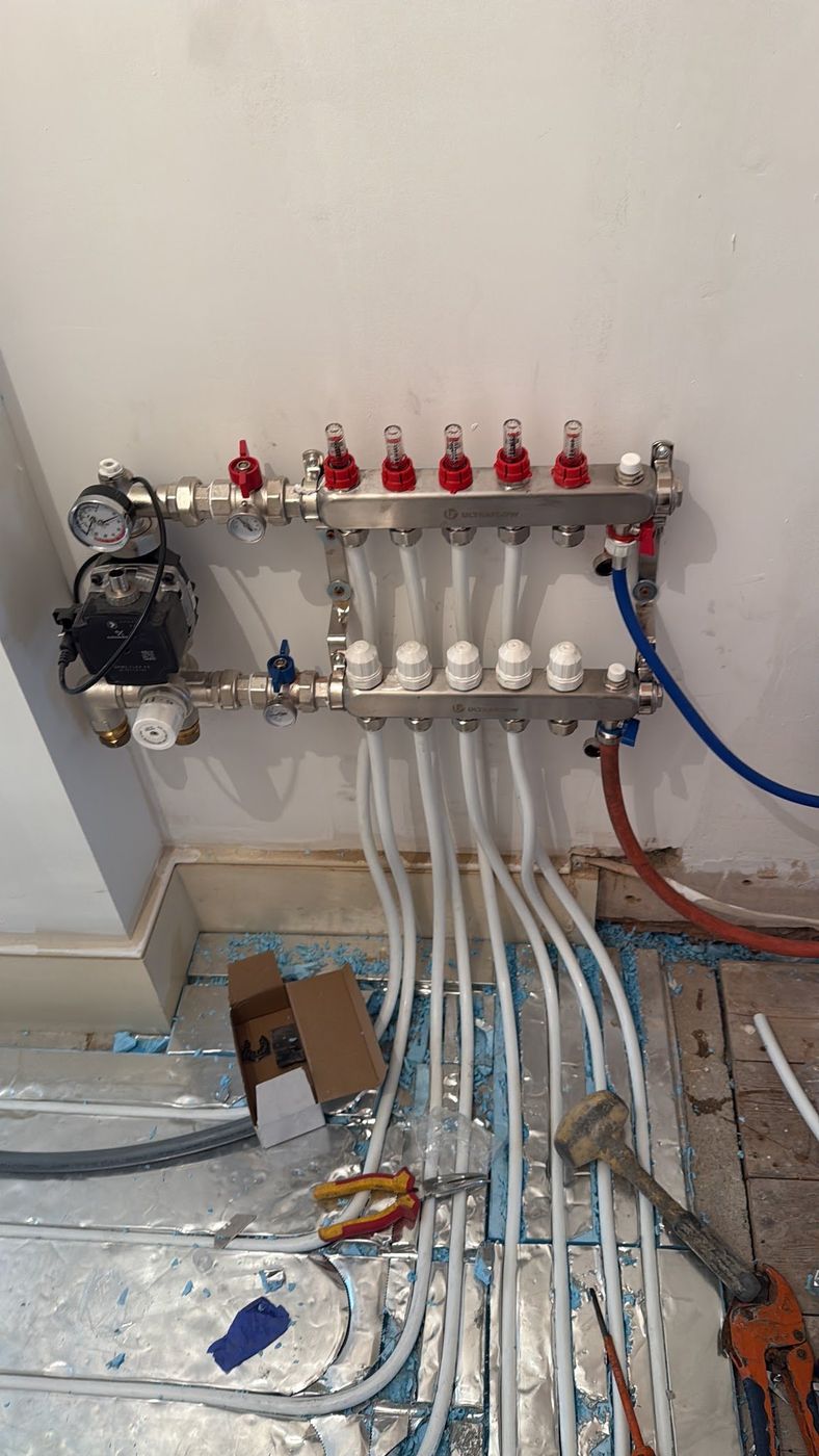 Underfloor heating manifold with PEX circuits running into the floor