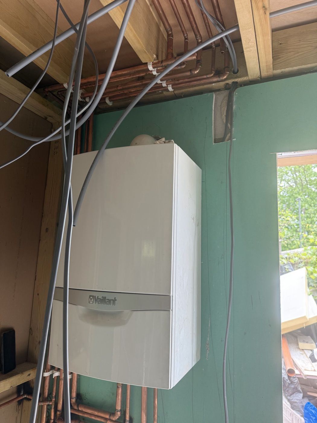 Wall-mounted Vaillant boiler with copper pipework running overhead